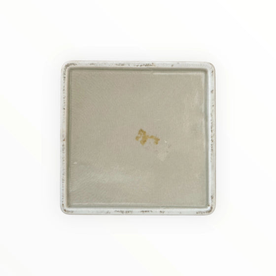 Rectangular ceramic tray with a textured surface and gold emblem on a white background