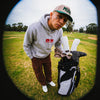 Pedro wearing the Play Your Best Structured Snapback Hat (Khaki/Green) and Bar Logo Hoodie (Grey) with Pin Stripes Golf Headcovers on his golf bag