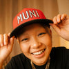 Woman wearing Muni Kids Play Your Best Structured Snapback Hat (Red/Black)